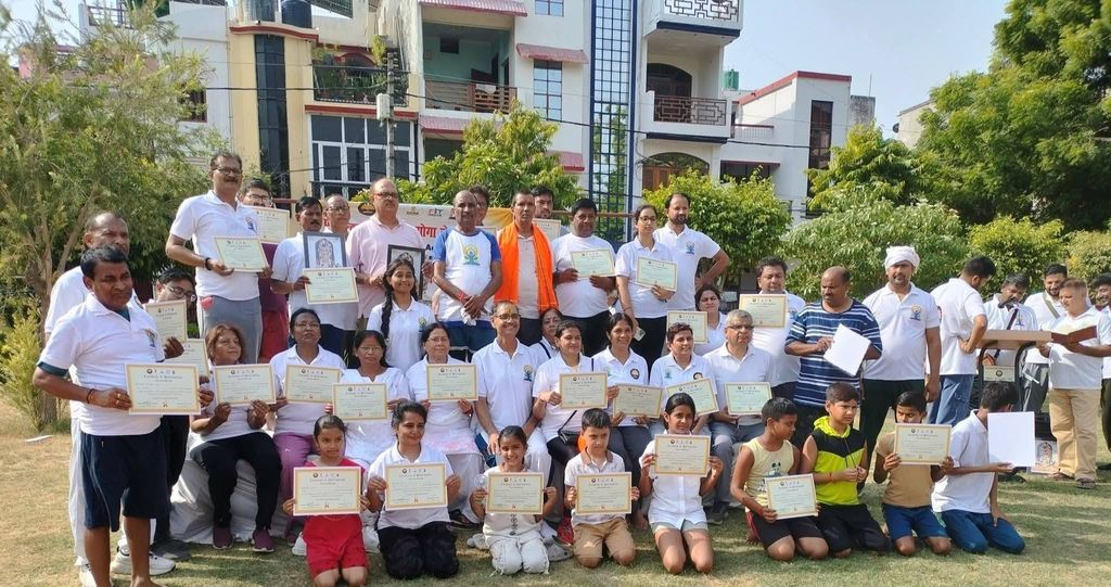 A large group of students of all ages standing and kneeling on a lawn, each holding a certificate